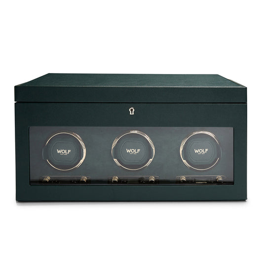 A stylish green watch winder, constructed with vegan leather, showcases three circular watch holders visible through a glass front. The brand "WOLF" is elegantly displayed on each holder, featuring a modern and minimalist design complemented by a subtle lock symbol above the panel.