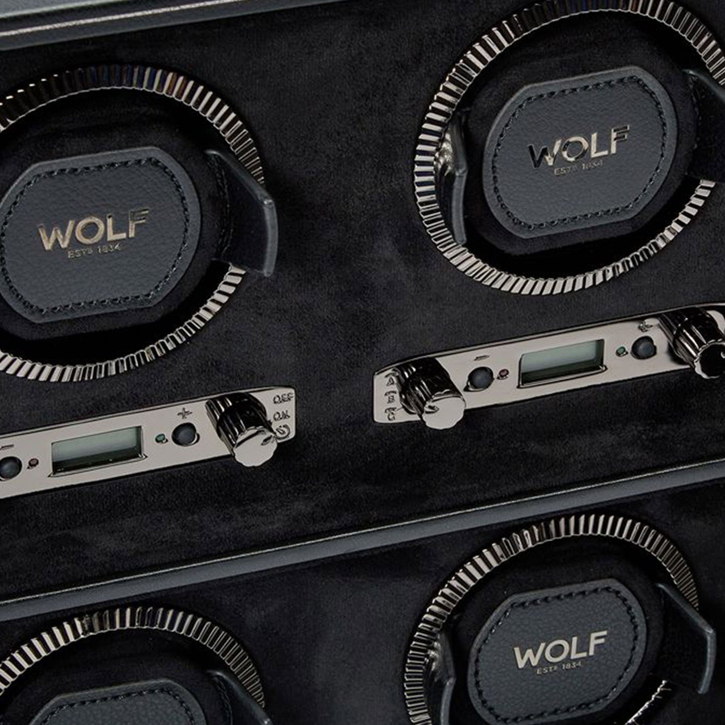 Close-up of the WOLF 1834 British Racing 6PC Watch Winder, featuring four slots and digital controls. The design boasts black leather inspired by British Racing aesthetics, complete with the iconic WOLF logo and metallic details, offering an elegant and functional setup for winding classic watches.