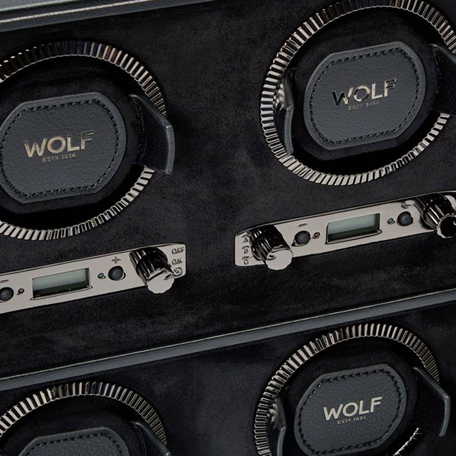 Close-up of the WOLF 1834 British Racing 6PC Watch Winder, featuring four slots and digital controls. The design boasts black leather inspired by British Racing aesthetics, complete with the iconic WOLF logo and metallic details, offering an elegant and functional setup for winding classic watches.