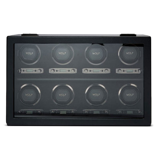 The WOLF 1834 British Racing 8PC Watch Winder, in black with a transparent glass front, elegantly displays eight watch slots arranged in two rows. Each slot includes a circular holder branded with "WOLF" and offers electronic controls for winding settings, capturing the timeless elegance of British Racing excellence.