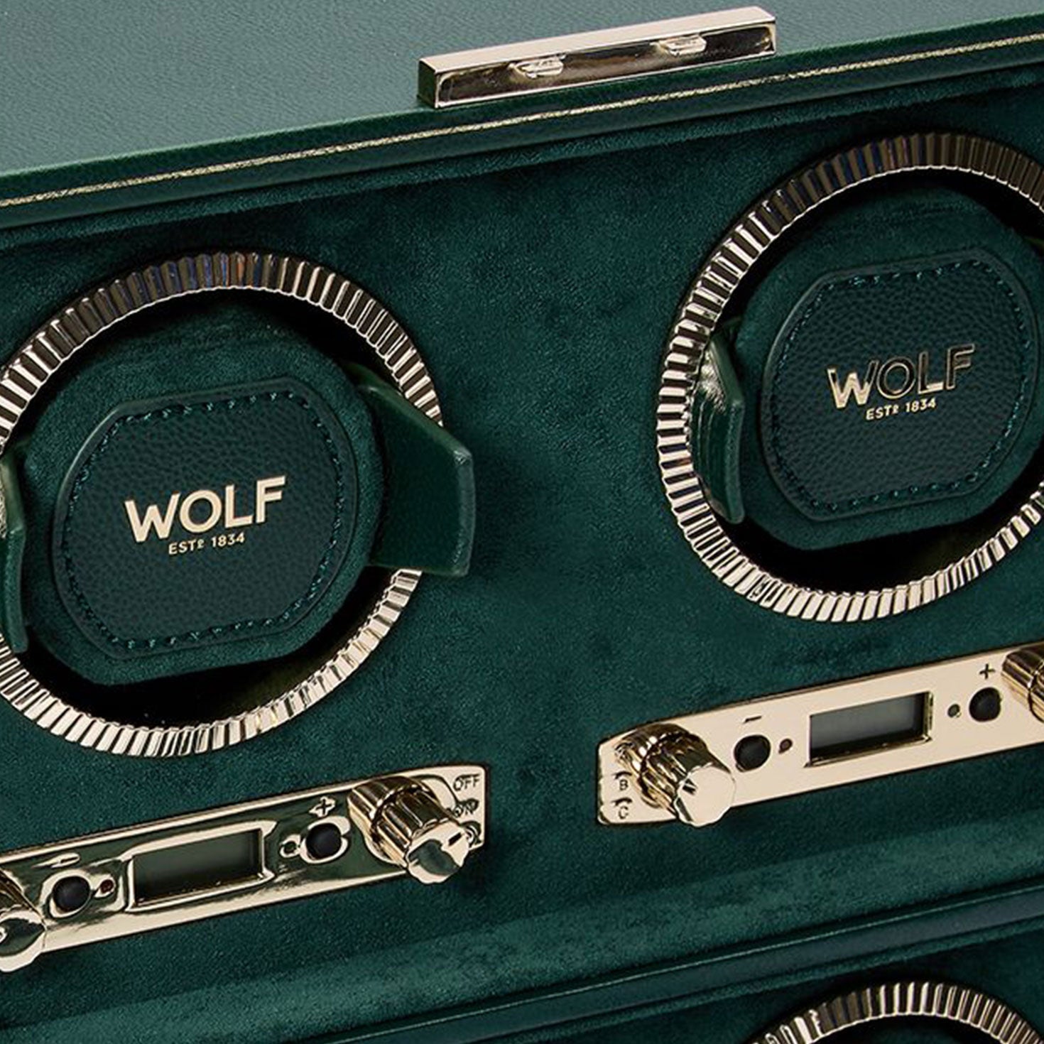 Close-up of the WOLF 1834 British Racing 4PC Watch Winder in luxurious green, showcasing "WOLF" and "EST 1834" on its rotating bezels. This classic piece features metallic controls and detailed dials for adjusting settings, embodying the elegance of British Racing heritage.