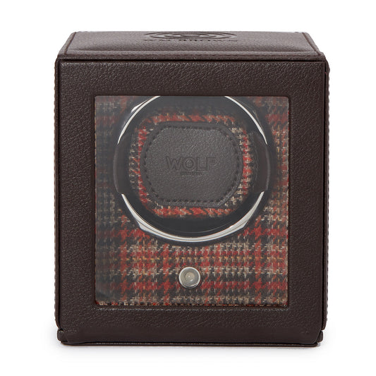 The WOLF 1834 WM Brown Single Watch Winder is a classic piece with a brown leather exterior and a glass front, showcasing the winder inside. The interior features a red and brown plaid pattern, and the holder is adorned with the "WOLF" brand name. It includes patented rotation programs designed for optimal watch care.