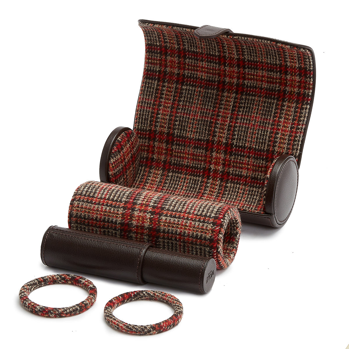 A travel set from WOLF, showcasing a plaid design and consisting of a passport holder, two luggage tags, and two elastic bands accented in red and brown leather tones. Displayed on a white background, the arrangement exudes the timeless elegance reminiscent of Negroni tweed lining.