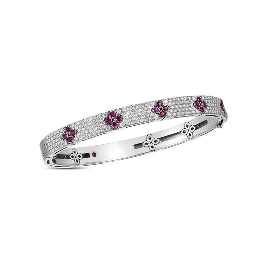 Introducing the Roberto Coin Love In Verona 18K White Gold Diamond Bangle. This exquisite piece features an intricate design with round diamonds and pink flower-shaped gems, forming multiple evenly spaced flower motifs around the bracelet. Crafted in silver and part of Roberto Coin's renowned collection, it is elegantly presented against a plain white background.