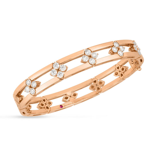 The Roberto Coin Love in Verona 18K Rose Gold Diamond Open Frame Bangle is a stunning piece featuring clusters of small, sparkling diamonds shaped like flowers. Its delicate open design with intersecting bands and floral accents showcases the exquisite craftsmanship that Roberto Coin is known for.