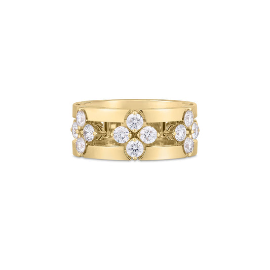 This Roberto Coin Love In Verona ring is crafted in 18K yellow gold and features a wide band with an intricate open frame design. It is embellished with clusters of round diamonds, each arranged in a floral pattern that symmetrically adorns the band.