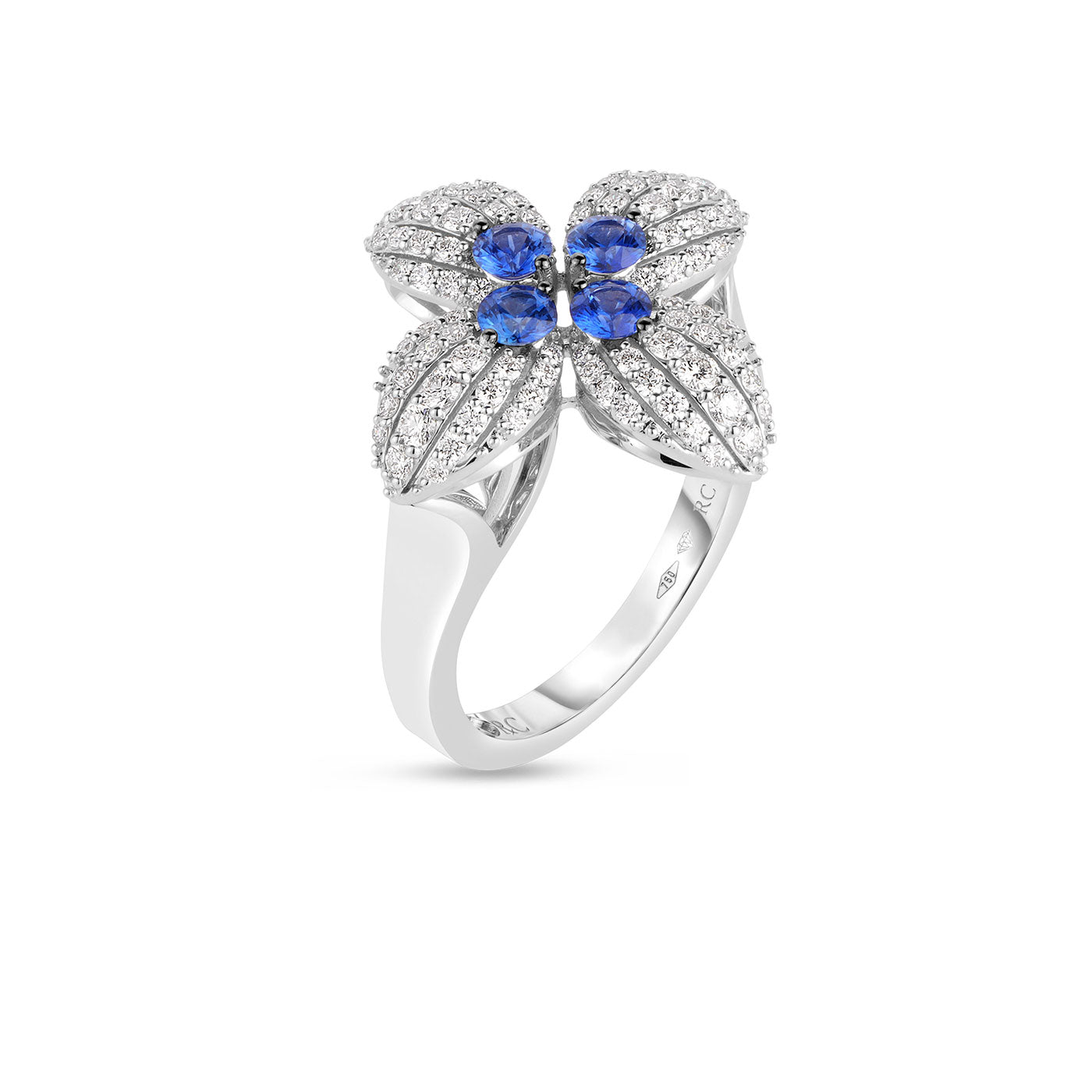 The Roberto Coin Love in Verona 18K White Gold Diamond and Blue Sapphire Flower Ring showcases a flower design with diamond-studded petals and four blue sapphires at the center, all set against a white background.