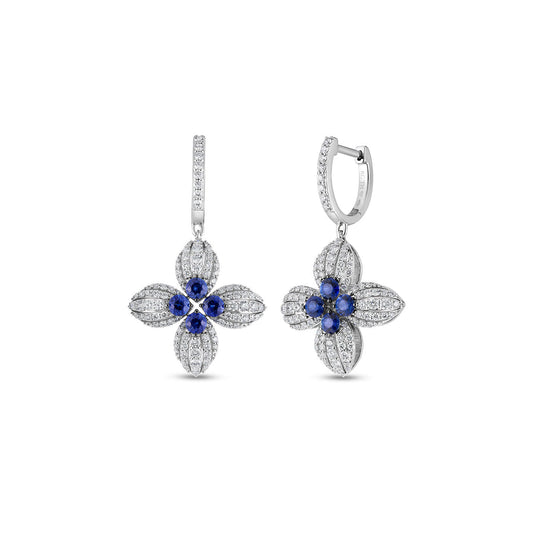 The Roberto Coin Love in Verona 18K White Gold Diamond and Blue Sapphire Flower Earrings exhibit a floral design with blue sapphire centers encircled by dazzling diamonds. These elegantly crafted earrings hang from simple hooks, reflecting the detailed craftsmanship and luxurious appeal synonymous with the Roberto Coin brand.