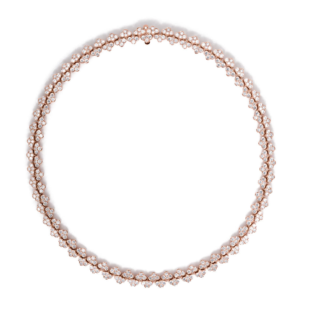 The Roberto Coin Cobra 18K Rose Gold Pave Diamond Collar Necklace showcases a repeating floral motif, each bloom adorned with sparkling pave diamonds and forming a complete circle against a white background. This striking piece from Roberto Coin elegantly fuses classic sophistication with modern design for a truly eye-catching statement necklace.