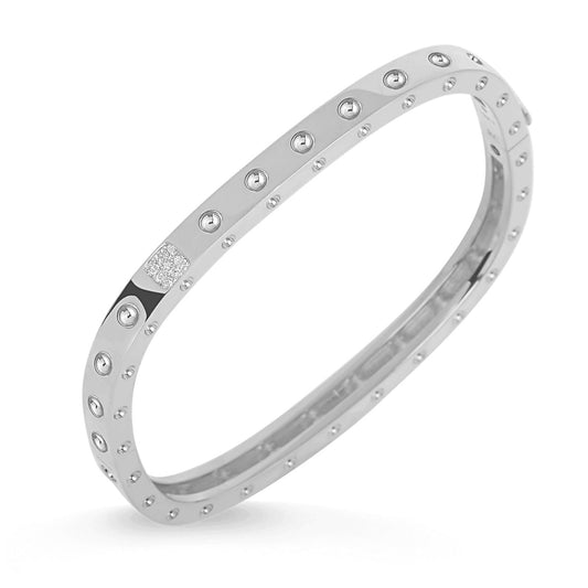 The Roberto Coin Pois Moi 18K White Gold Diamond Accent Square Bangle, created by the brand Roberto Coin, showcases an elegant array of embedded circular studs and a cluster of tiny diamonds at the top. Its sophisticated angle emphasizes the exquisite design and radiance against a white background.