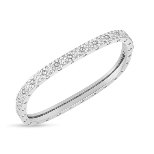 A stunning square-shaped bangle crafted from 18K white gold, the Roberto Coin Pois Moi bangle is adorned with a single row of sparkling pave diamonds. Its smooth, polished surface and detailed edges impart an elegant and luxurious feel, embodying the timeless aesthetic of Roberto Coin's designs.