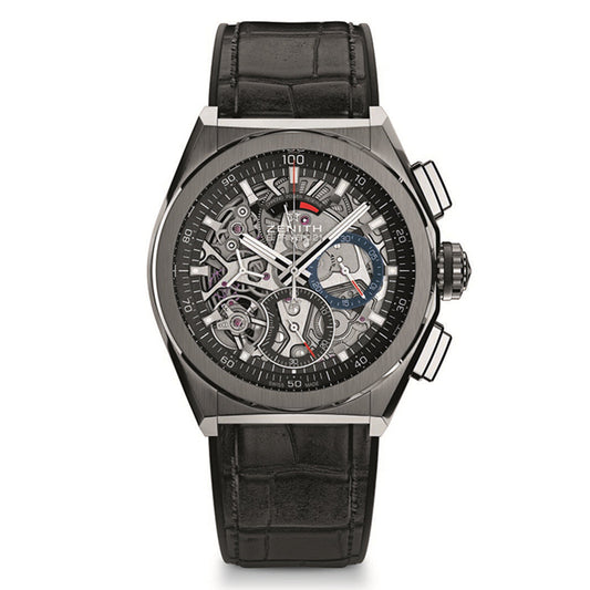 The Zenith Defy El Primero 21 features a silver-toned case, a black leather strap, and an intricate skeleton dial showcasing its gears. It includes two push buttons on the side.