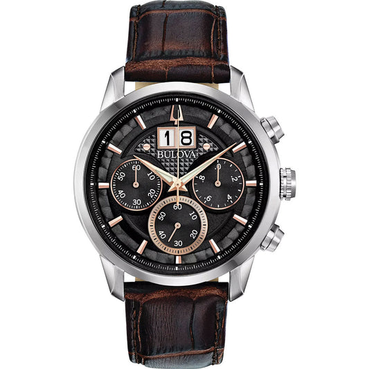 The Bulova Sutton Classic Quartz 44mm men's watch features a black textured dial, three subdials, large date display, silver and rose gold-tone markers, and a brown crocodile-pattern leather strap.