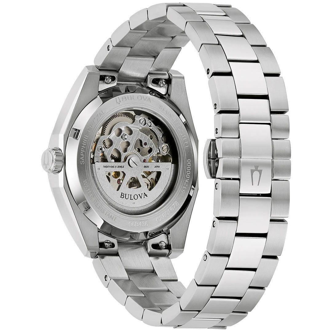 A close-up of the Bulova Surveyor Automatic 39mm Watch highlights its silver stainless steel bracelet and the exposed automatic movement with intricate gears, visible through the transparent case back.