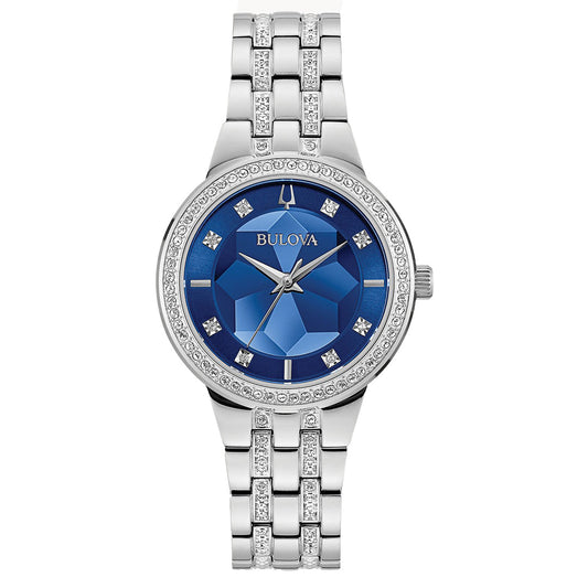 The Bulova Phantom Quartz 32.5mm watch exhibits a blue faceted mineral glass dial, adorned with diamond hour markers and a gem-like texture. Its bezel and bracelet are embellished with crystals, enhancing its luxurious appearance.