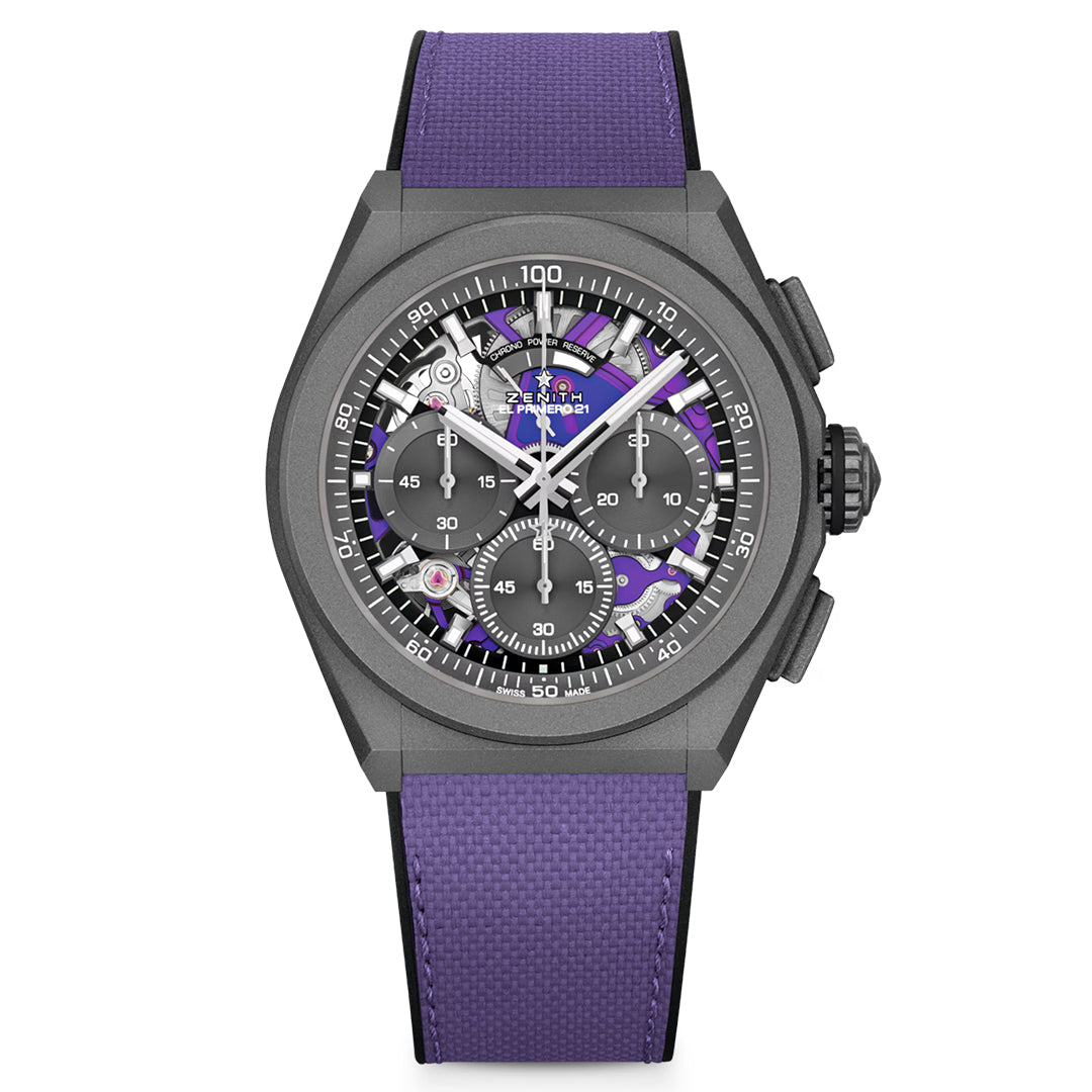 The ZENITH Defy El Primero 21 44mm Watch features a purple strap and detailed face with visible gears. With a tachymeter scale on the bezel, multiple sub-dials, and crafted from matte titanium, it exudes sophistication in its dark metallic case.