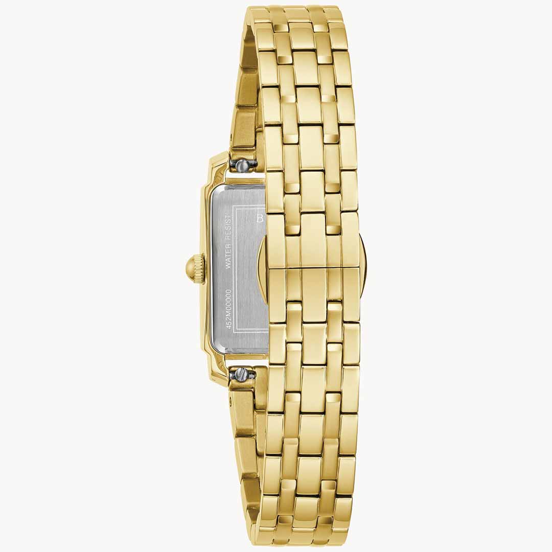 The Bulova Sutton Quartz 21mm women's watch is shown from the side, highlighting its gold-tone stainless steel construction with a rectangular case and woven metal band. The watch is expertly positioned to showcase the stainless steel back, complete with visible screws and crown, all set against a plain white background.