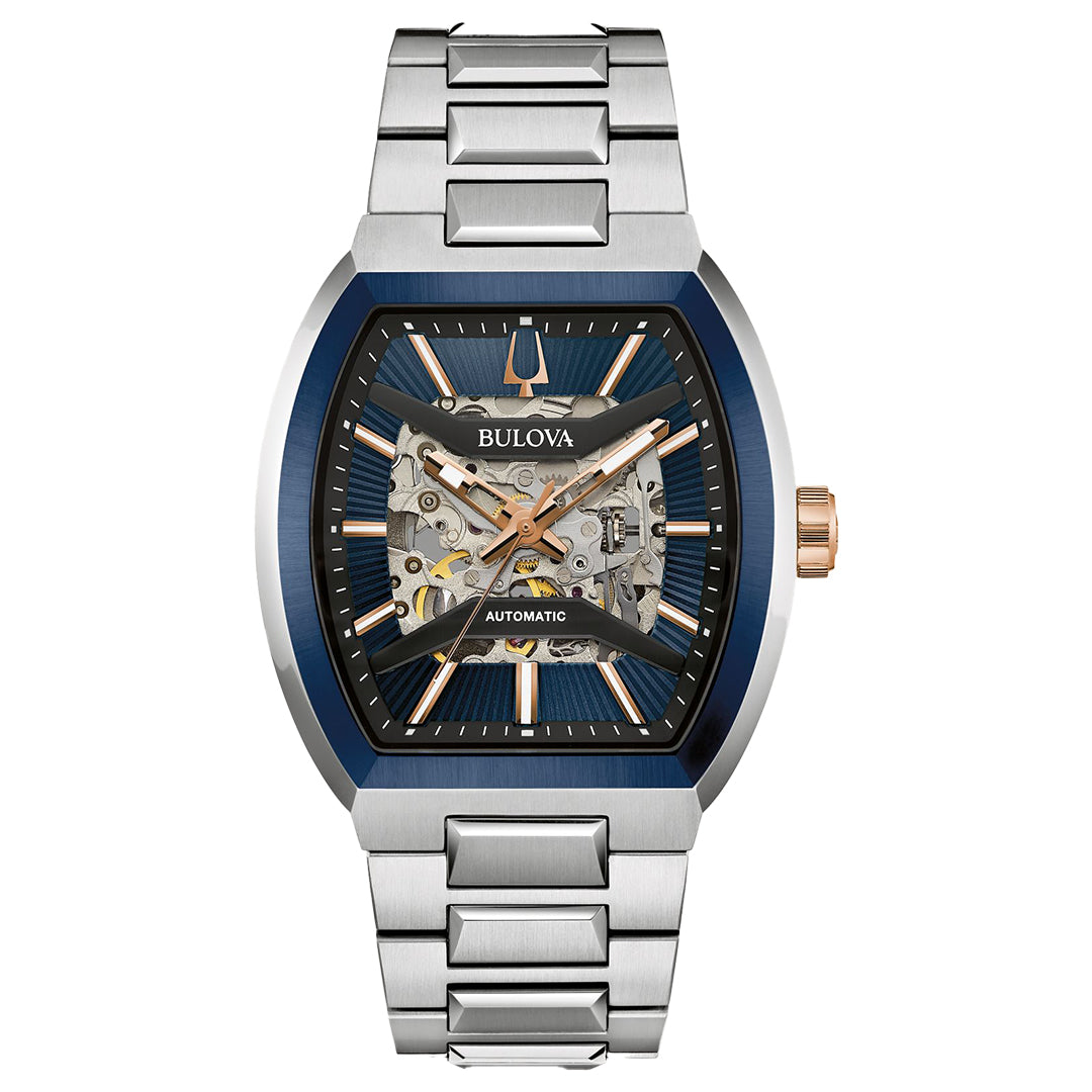 The Bulova Maquina Automatic 40mm Watch features a silver metal band, blue and silver tonneau-shaped case, partially open skeleton dial with rose gold accents, and exposed internal gears.