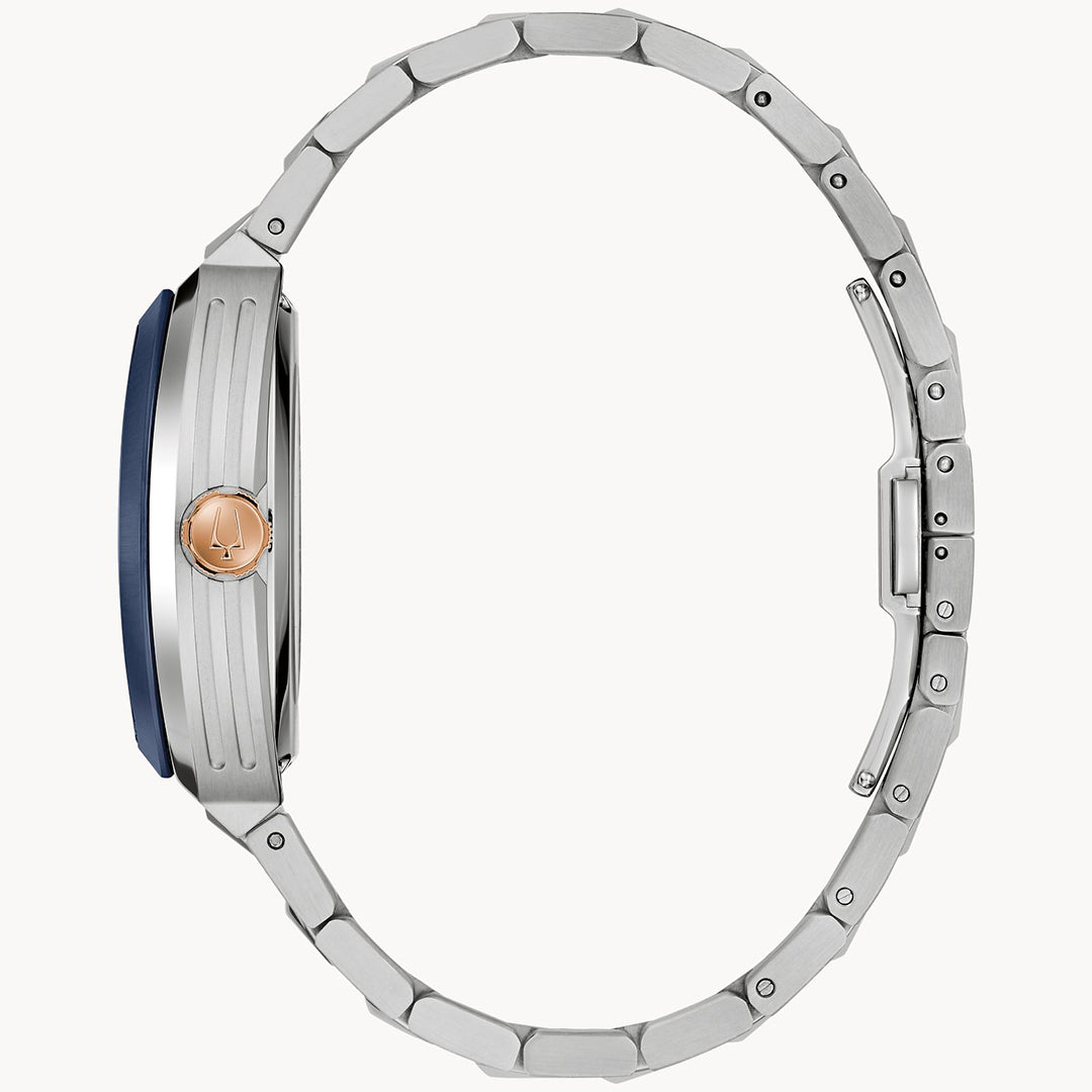 Side view of the Bulova Maquina Automatic 40mm Watch by Bulova, featuring a silver metal bracelet, blue-accented case, and gold-tone crown, displayed closed against a plain white background.