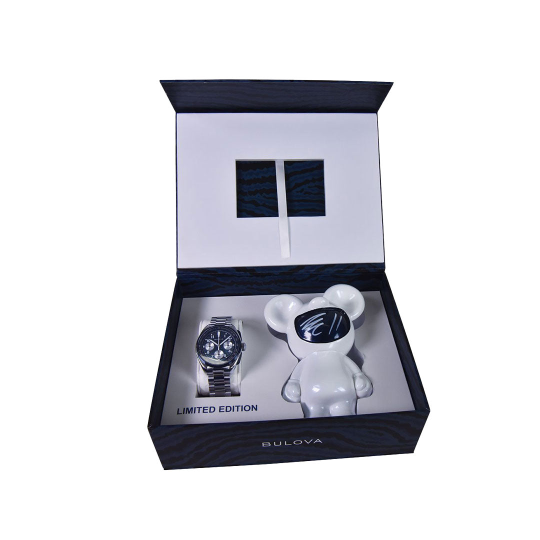 An open Bulova box reveals the Lunar Pilot Timascus Quartz 43.5mm Limited Edition watch, known for its titanium Damascus design, and a white bear figurine with a black face, both neatly arranged inside. Limited to 5,500 pieces.