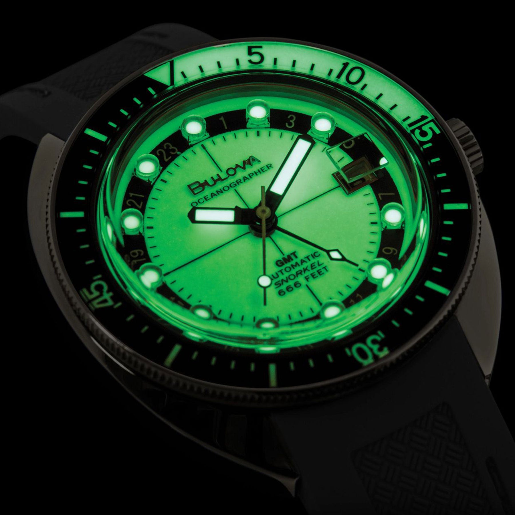 A close-up of a luminous men's watch face glowing green in the dark showcases the Bulova Oceanographer Automatic GMT 41mm Watch. It features a rotating bezel, prominent hour markers, and bold hands. The dial displays the brand name and details over a shadowed background, highlighting its self-winding GMT movement.