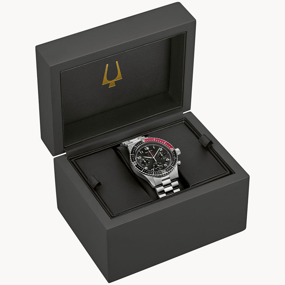 The Bulova Marine Star Heritage Quartz 42.85mm Limited Edition watch, featuring a black and red bezel and black dial, is displayed in an open black box with a gold trident logo, highlighting its chronograph functionality.