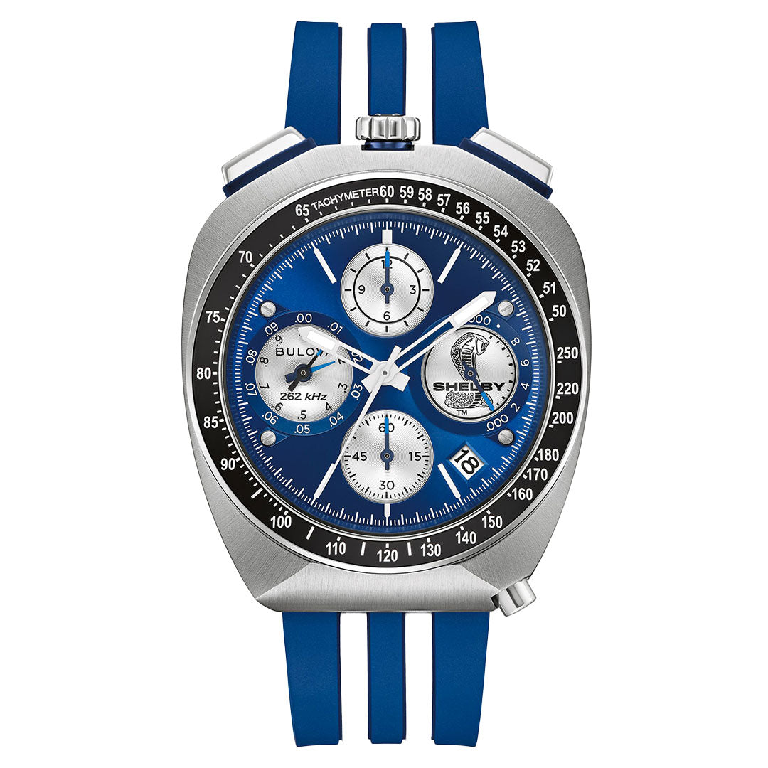 The Bulova Shelby Racer Chronograph Quartz 43mm Watch, limited to 7,500 pieces, features a blue/silver dial with “Shelby Cobra” branding, three subdials, date at 4 o’clock, tachymeter bezel, and blue rubber strap.