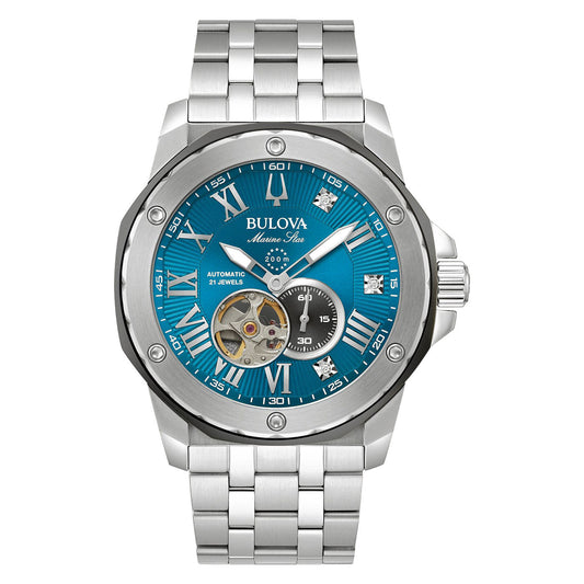 The Bulova Marine Star Marc Anthony Automatic 45mm Watch is a stainless steel timepiece featuring automatic movement, a silver design with a blue face, and elegant Roman numerals. It showcases visible gears and a small sub-dial, complemented by a metal link bracelet and a silver bezel with screws.