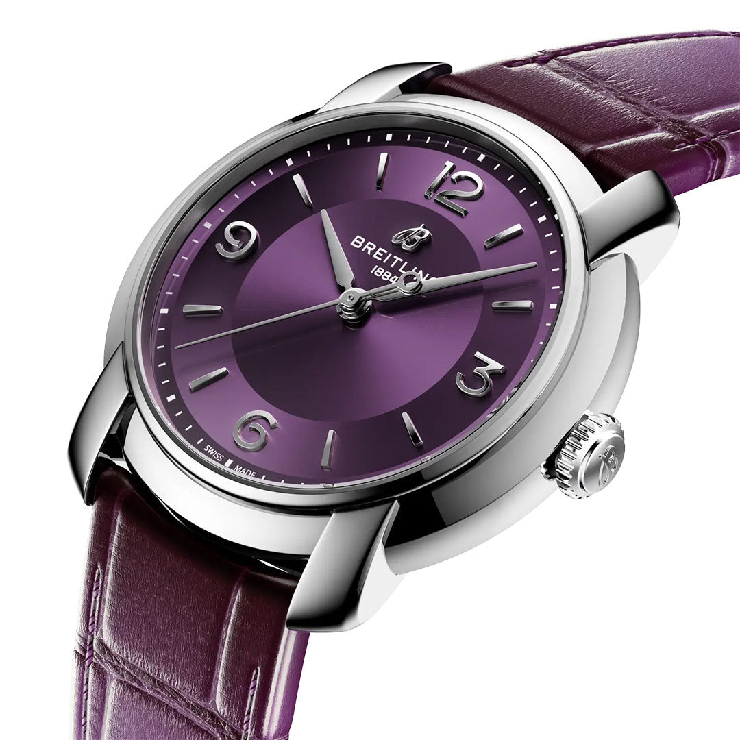 The Breitling Lady Premier Automatic 36, featuring a metallic purple dial with silver hour markers and a matching purple leather strap, is displayed at an angle on a white background.