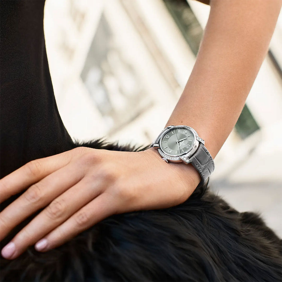 A person wearing a Breitling Lady Premier Automatic 36 luxury wristwatch rests their hand on a black, fur-like surface. The softly blurred background highlights the wristwatch and hand.