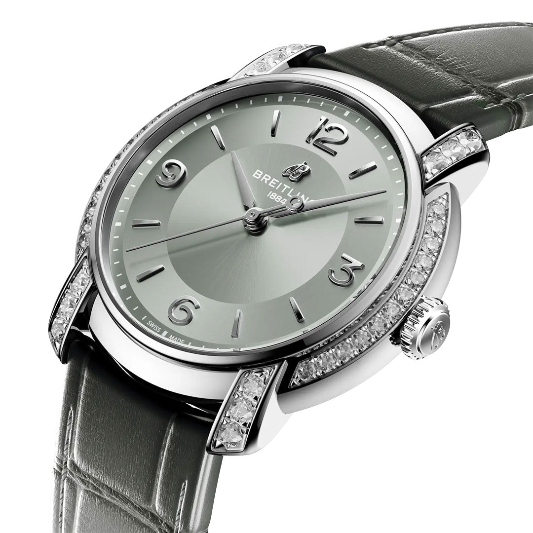The BREITLING Lady Premier Automatic 36 by Breitling features a silver dial, silver markers, and a gray leather strap. Diamond-set bezel and lugs give this women's watch an elegant, sophisticated look.