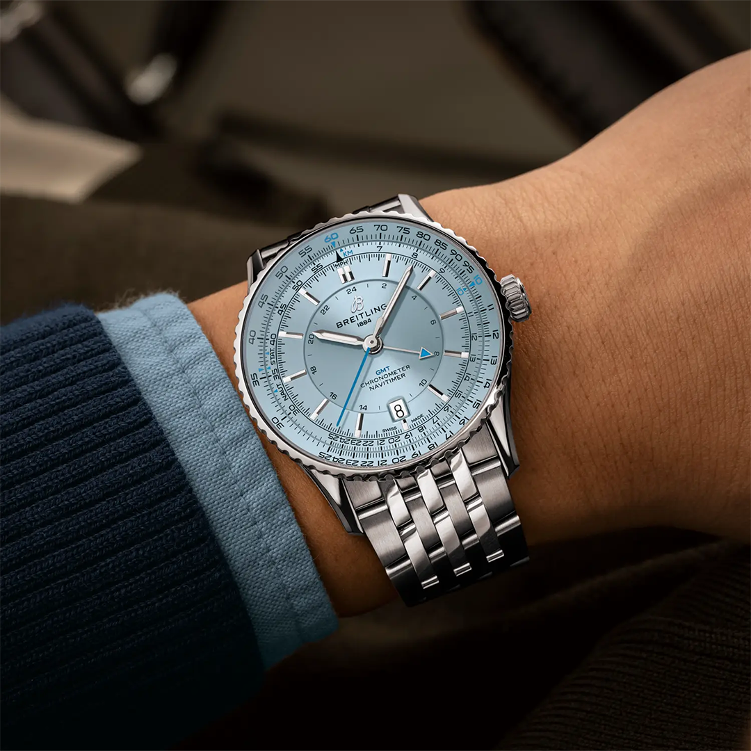 A silver-toned BREITLING Navitimer Automatic GMT 41 watch with a light blue dial, GMT hand, and a metal link bracelet worn on a wrist.