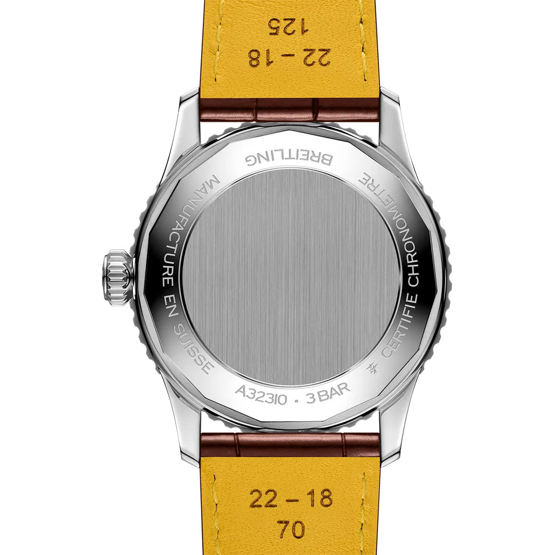 The back of the BREITLING Navitimer Automatic GMT 41 features a brushed metal case with engraved model numbers, water resistance, and certification details, complemented by a yellow leather strap.