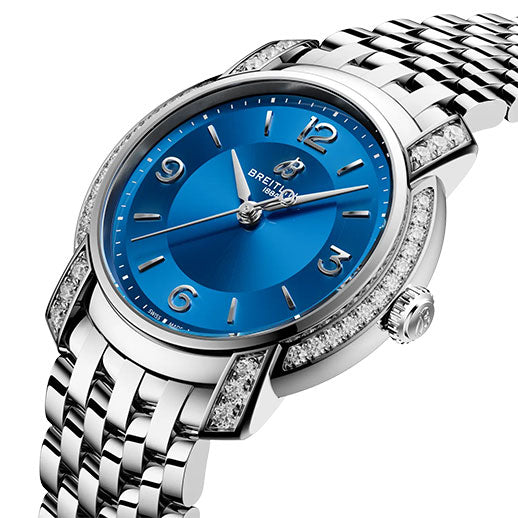 The Breitling Lady Premier 32, a silver watch with a blue dial, silver hour markers, diamond-accented bezel, and polished link bracelet by Breitling, is displayed at an angle on a white background.