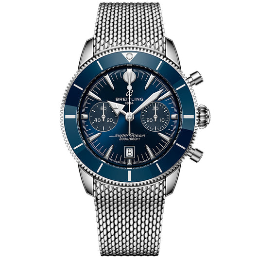 The Breitling Superocean Heritage B01 Chronograph 42 features a blue dial with three subdials, date at 6 o’clock, silver bezel, and stainless steel mesh bracelet, powered by the Breitling Manufacture Caliber 01. Shown on white background.
