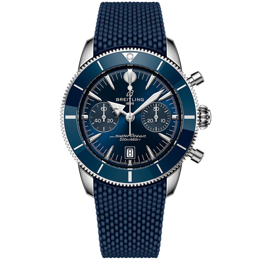 The Breitling Superocean Heritage B01 Chronograph 42 features a blue dial with three subdials, a date window, silver indices, a textured blue rubber strap, and a ceramic bezel with silver edging.