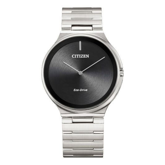 The CITIZEN Stiletto Eco-Drive 39mm Watch offers a sophisticated, round black dial with a minimalist design. It includes a metallic bracelet band and features understated silver hour and minute hands. The face prominently showcases the CITIZEN logo alongside the "Eco-Drive" technology text.