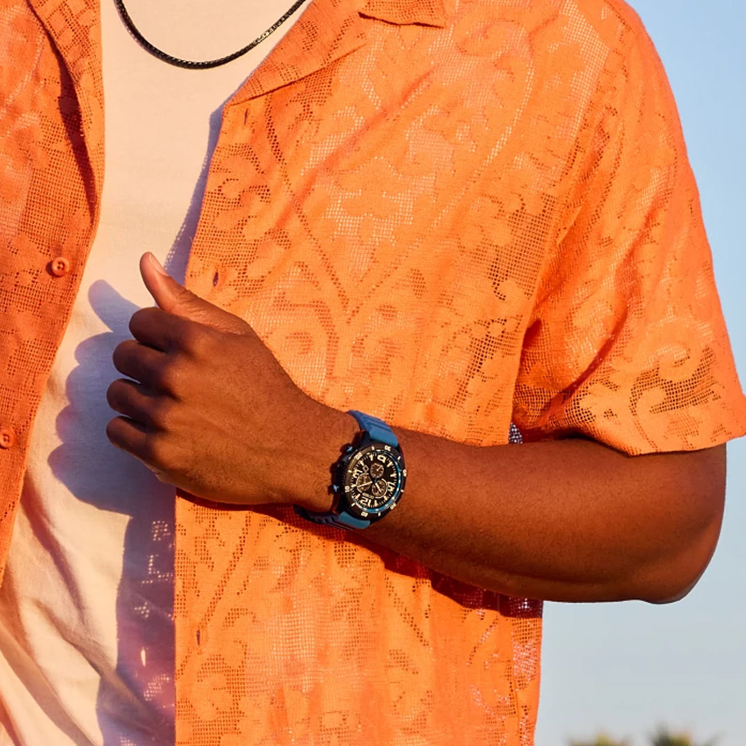 Wearing a CITIZEN Brycen Eco-Drive 44.8mm watch, a person in a white and orange patterned short-sleeve shirt adjusts their sleeve to reveal the sleek timepiece on their wrist.