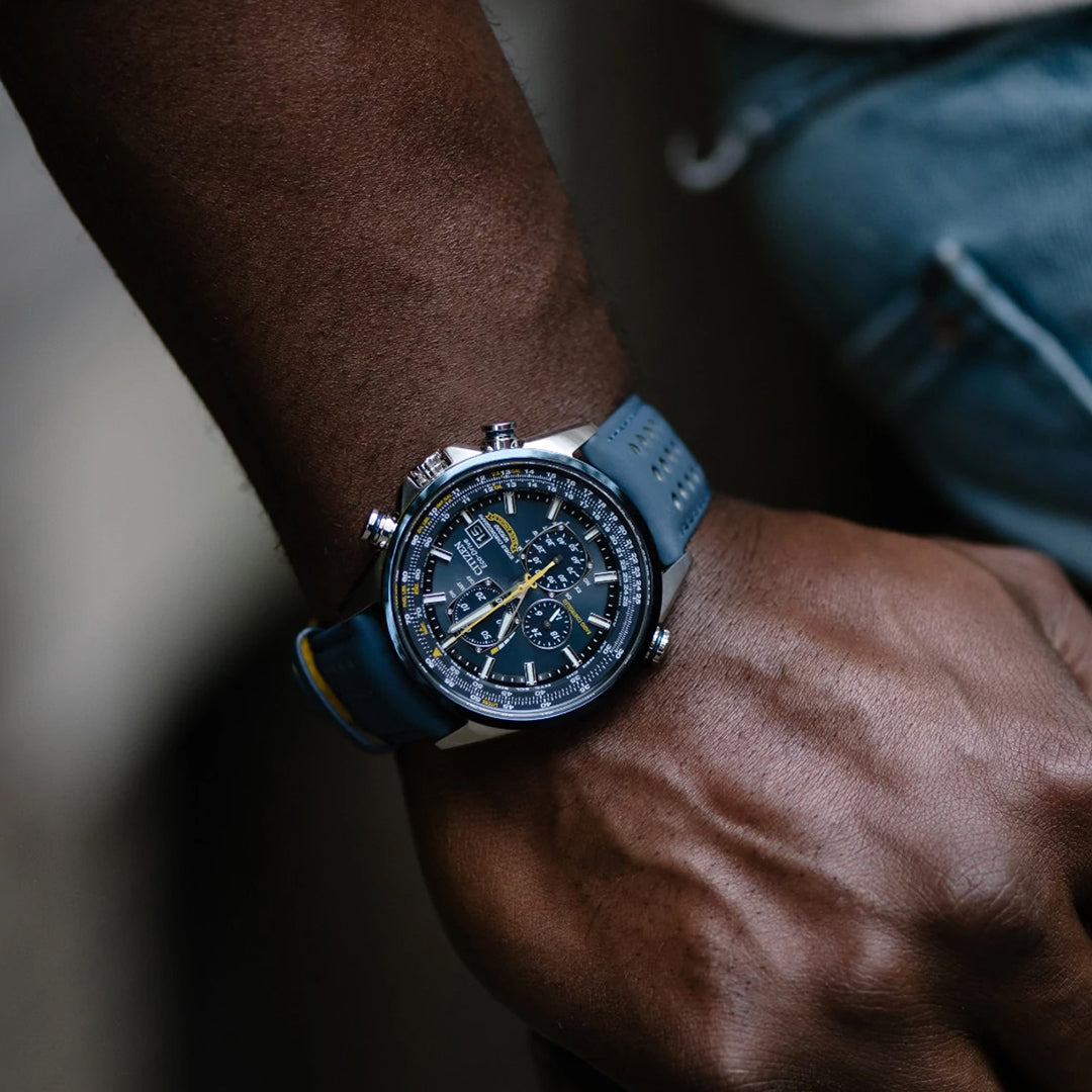 The individual wears the CITIZEN Blue Angels World Chronograph AT Eco-Drive 43mm Watch, featuring a detailed face and silver casing with a blue strap, which stands out against their casual denim outfit.