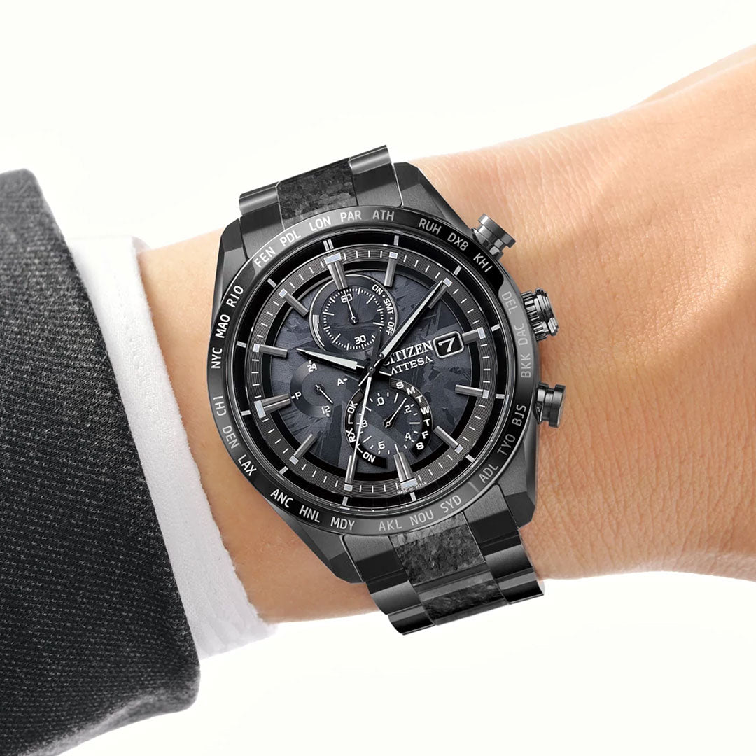 A close-up of a wrist wearing the CITIZEN Attesa Hakuto-R Atomic Time Keeping Super Titanium Limited Edition Eco-Drive 42mm Watch, featuring a silver metal band, shown against a white background with a dark suit sleeve and white shirt cuff.