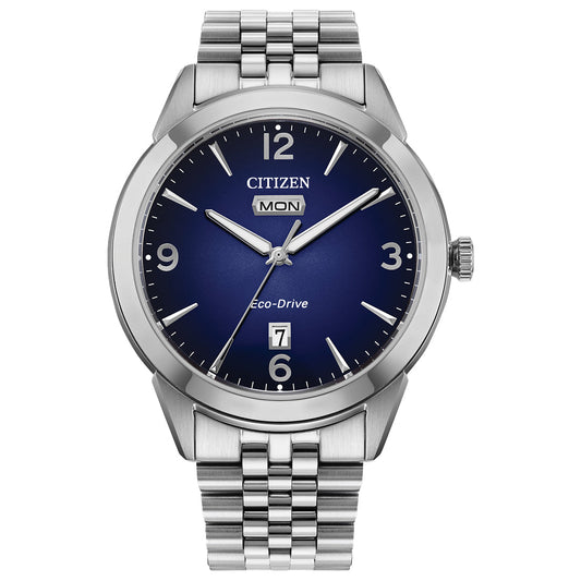 The CITIZEN Rolan Eco-Drive 40.5mm Watch showcases a vintage-inspired design with a stainless steel bracelet, blue dial, silver hands, white hour markers, and day-date display. Its sleek silver bezel enhances the timeless elegance associated with this CITIZEN piece.