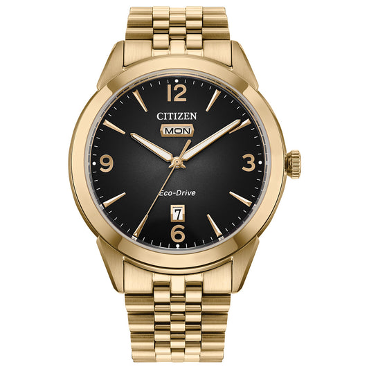 The CITIZEN Rolan Eco-Drive 40.5mm watch is a vintage-inspired timepiece featuring a black dial, gold markers, Arabic numerals at 12, 3, 6, and 9, a day-date display at 3 o'clock, and a matching gold link bracelet.