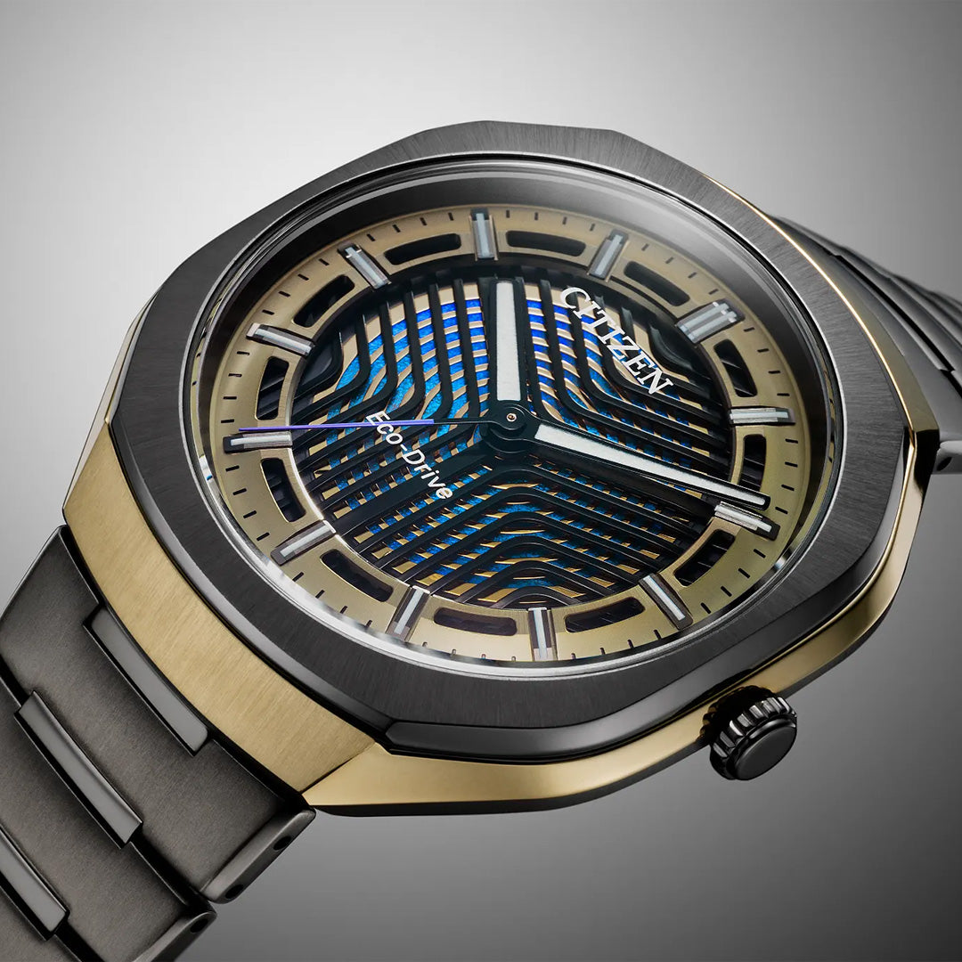 A close-up of the CITIZEN Photon Eco-Drive 39.6mm Watch Limited Edition, featuring a black and gold two-tone case, metallic band, and a patterned blue and gold dial accented with silver hands and markers.