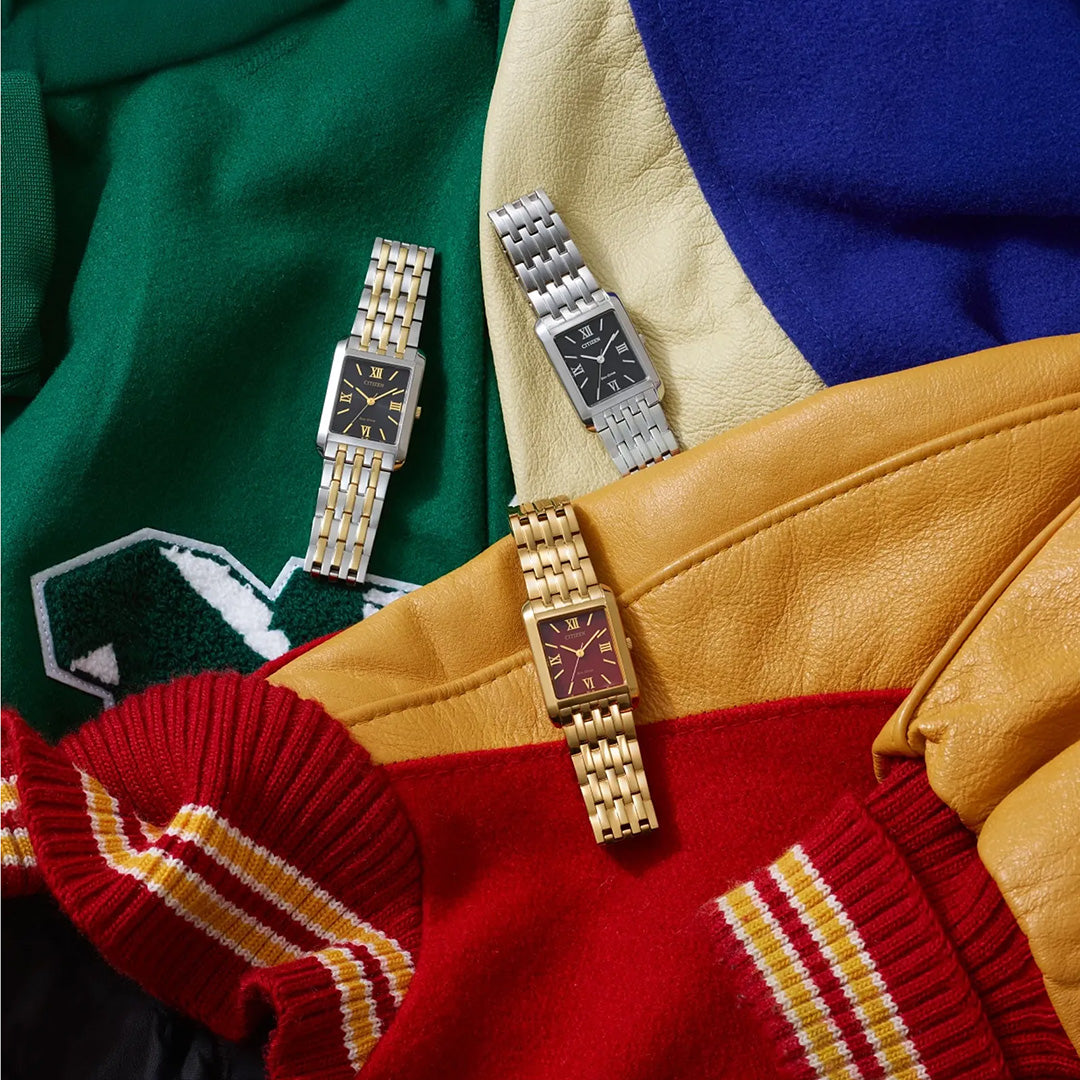 Three CITIZEN Addysen Eco-Drive 26.5mm rectangular dress watches with stainless steel bands are displayed on colorful varsity jackets—green, blue, yellow, and red with striped cuffs. The CITIZEN watch faces come in black, gold, and burgundy, each adorned with Roman numerals.
