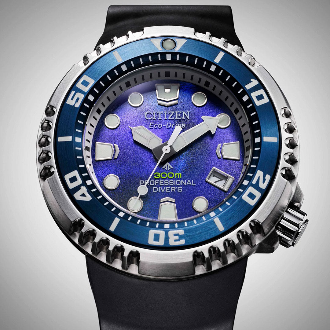 A close-up of the CITIZEN Promaster Dive Eco-Drive 46mm Limited Edition shows a blue dial, bold luminous markers, blue bezel, and a black strap. This professional diver’s watch by CITIZEN is water-resistant up to 300m.