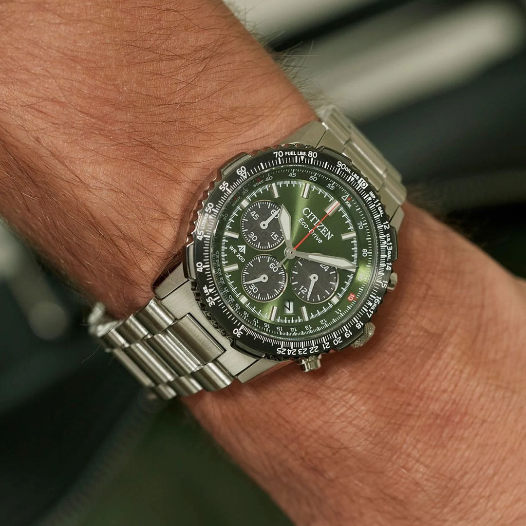 A close-up of a person’s wrist wearing a CITIZEN Promaster Navihawk Eco-Drive 40mm Watch, featuring a green dial, silver case, stainless steel bracelet, multiple subdials, and white markings.