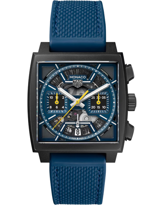 A TAG Heuer Monaco Chronograph Automatic 39mm watch with a square face, featuring a blue strap, a blue and black dial, yellow hands, and two subdials, shown on a plain white background.