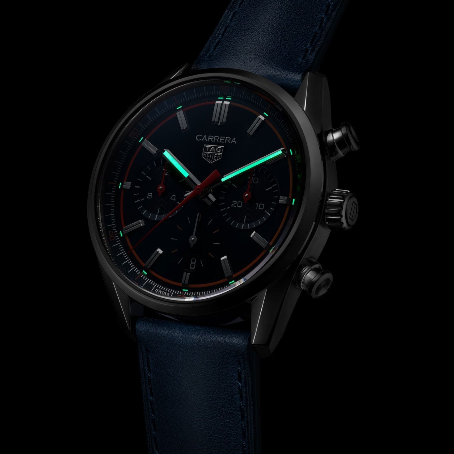 Introducing the TAG Heuer Carrera Chronograph Automatic 42mm Watch by TAG Heuer—a sophisticated timepiece featuring a black case, dark dial, glowing green hands, bold red accents, and two functional subdials powered by the advanced Calibre HEUER02 movement. Finished with a blue leather strap and presented against a sleek black background, this watch epitomizes elegance and modern design.