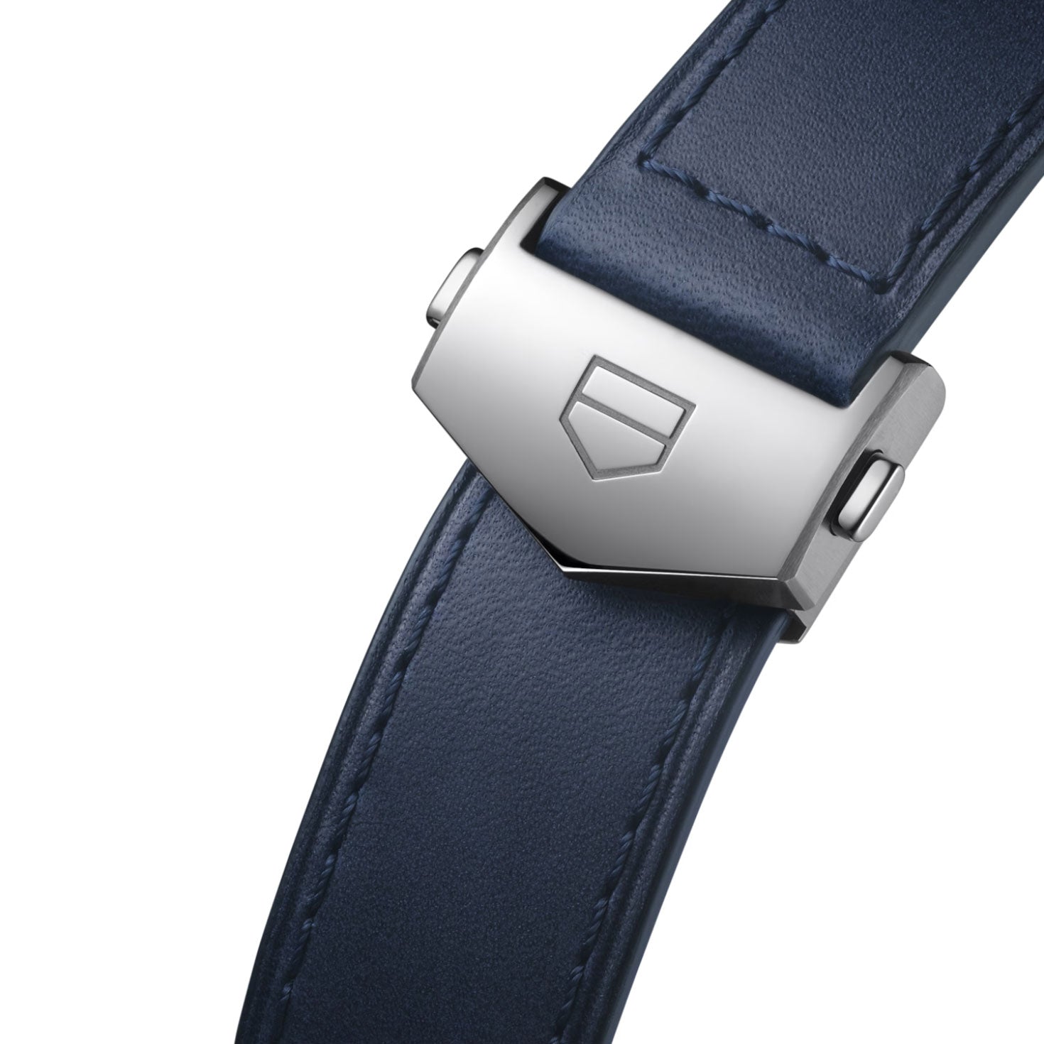 Close-up of a dark blue leather watch strap with a silver clasp featuring an embossed shield-shaped logo. The white background accentuates the stitching and metallic details, capturing the refined craftsmanship characteristic of the TAG Heuer Carrera Chronograph Automatic 42mm Watch by TAG Heuer.