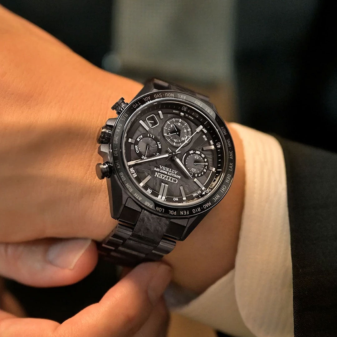 A person in a suit with a white shirt and dark jacket checks the time on a CITIZEN Attesa Hakuto-R Atomic Time Keeping Super Titanium Limited Edition Eco-Drive 44.6mm watch.